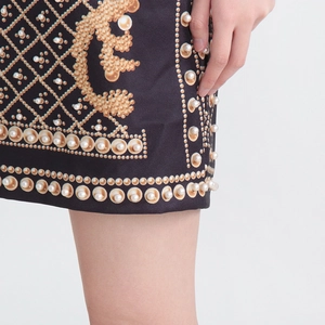Détail de broderie de perles et imprimé floral doré sur robe trapèze noire