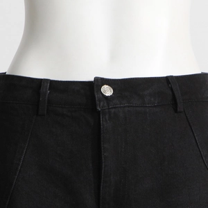 Dettaglio vita dei jeans neri a vita alta con bottone in argento inciso e passanti