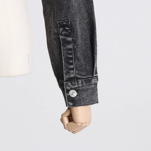 Λεπτομέρεια macro από πλυμένο denim μανίκι με μεταλλικό κουμπί και σταυρωτή ραφή