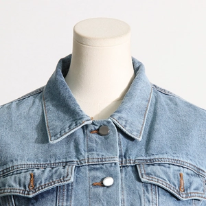 Detail of light blue denim jacket collar with contrast stitching and metal button