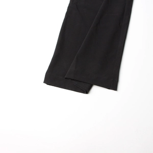 Détail des coutures nettes et de l'ourlet sur le pantalon noir d'une élégante combinaison