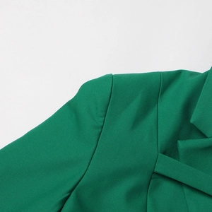 Détail d'un blazer vert émeraude montrant le tissu tissé et les coutures de l'épaule