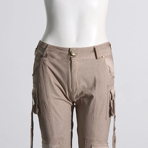 Detail of khaki cargo trousers showing large utility pockets and ribbon strap decor