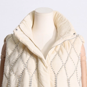 Detail of beige quilted puffer vest featuring sparkling rhinestone lattice and stand collar