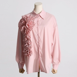 Dettaglio di camicia rosa chiaro a maniche lunghe con applicazione di fiore 3D plissettato