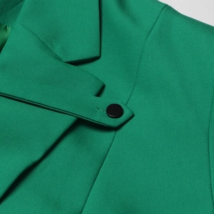 Détail du revers et de l'épaule du blazer vert avec tissu sergé de haute qualité et bouton