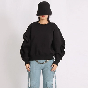 Detailed view of layered pleats and ruched sleeve design on a black crewneck sweatshirt