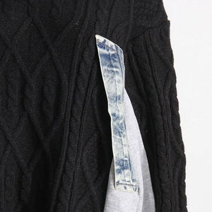 Detail of cable-knit black sweater featuring unique blue denim and grey patchwork