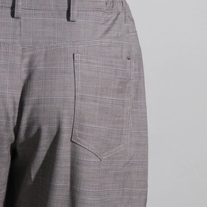 Détail du pantalon à carreaux gris montrant les coutures de la poche arrière et des passants