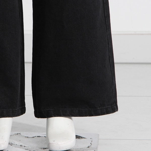 Dettaglio dei pantaloni larghi in denim nero che mostrano orlo e trama del tessuto