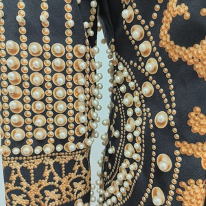 Détail de perles brodées sur une robe noire à manches longues et imprimé floral rétro