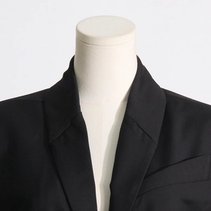 Detail of the collar and shoulder of a black blazer on a white mannequin