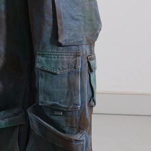 Gros plan d'un pantalon cargo en denim épais avec délavage multicolore et grandes poches