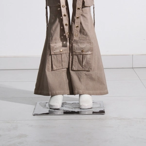 Detail view of khaki flare cargo pants featuring large 3D pockets and metal eyelet ribbons