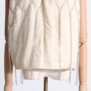 Detailed view of cream puffer vest with silver rhinestone fringe and pleated texture
