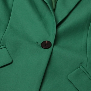 Vue détaillée du tissu blazer vert avec bouton noir et rabats de poches élégants