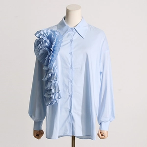 Dettaglio camicia azzurra a maniche lunghe con grande fiore a pieghe 3D e colletto classico