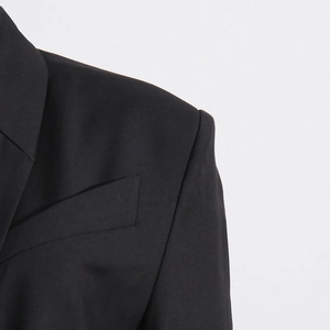 Close-up of black blazer shoulder with sharp tailoring and textured diagonal weave fabric