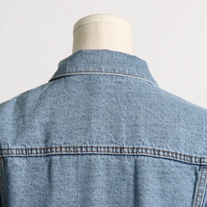 Detailed macro view showing the double-stitched seams on the light blue denim jacket collar