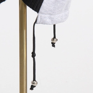 Detailed view of the contrast stitching and drawstring with metal beads on a knit sweater