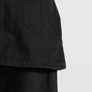 Dettaglio del denim nero carbone che mostra la tasca pentagonale e cuciture precise