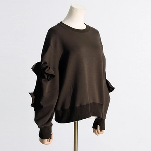Detailed close-up of dark brown sweatshirt with ruffled sleeves and ribbed cuffs