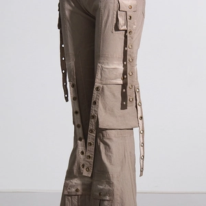 Close-up of light brown cargo pants featuring decorative eyelet ribbons and utility pockets