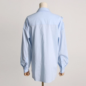 Dettaglio del retro della camicia azzurra con carré posteriore e spalle scese ampie