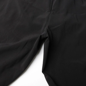 Détail de la texture lisse du tissu noir et des coutures précises sur le pantalon combi