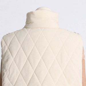 Detail of cream quilted vest with stand-up collar and rhinestone shoulder accents