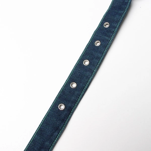 Detail of dark blue denim belt with silver metal eyelets and green contrast stitching
