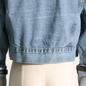 Close-up of light blue cropped denim jacket back with orange contrast stitching details