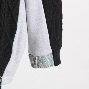 Detailed close-up of cable knit sweater with denim cuffs and silver metal buttons