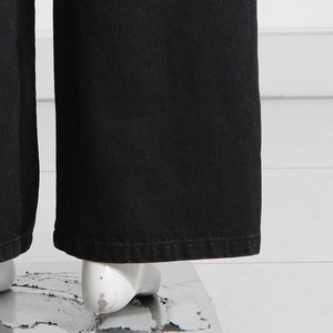 Dettaglio dell'orlo a doppia cucitura e della trama twill dei jeans neri a gamba larga