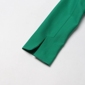 Détail du revers de manche d'un blazer vert avec fente asymétrique et coutures fines