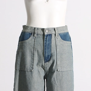 Detail of high-waisted contrast patchwork denim pants with large pockets and metal button