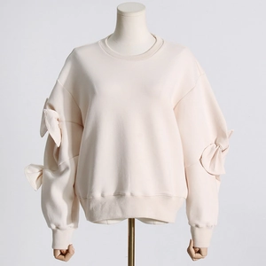 Detail of beige crewneck sweatshirt featuring pleated bow knots on drop shoulder sleeves