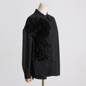 Dettaglio del fiore in tessuto plissettato 3D su camicia nera a maniche lunghe da donna