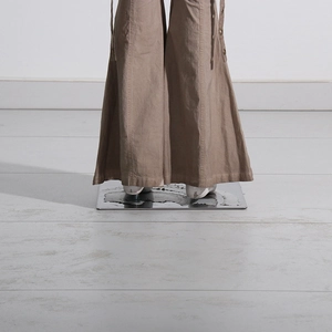 Detail view of khaki flare trousers featuring side metal buttons and decorative straps