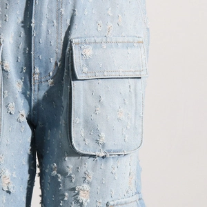 Détail d'un jean bleu clair déchiré montrant les poches cargo et la texture du tissu usé