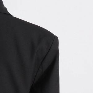 Close-up of black blazer shoulder seam showing high-quality twill fabric texture