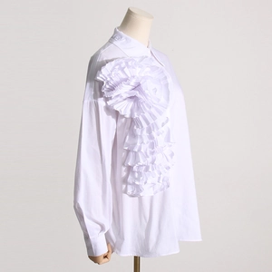 Dettaglio della decorazione floreale plissettata 3D su camicia bianca a maniche lunghe