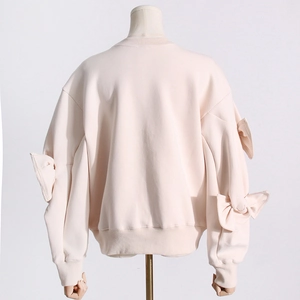 Rear view detail of a beige crewneck sweatshirt featuring stylish 3D bow accents on sleeves