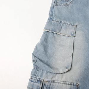 Detail view of the side cargo pocket and washed denim texture of the light blue jumpsuit