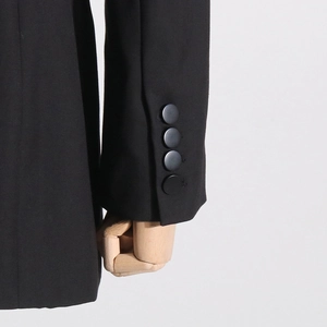Detailed macro view of high-quality black blazer sleeve with four matte round buttons