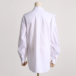 Vista posteriore di una camicia bianca oversize con dettaglio cuciture e spalle scese