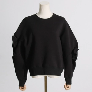 Close-up of crewneck sweatshirt featuring 3D bow detailing on sleeves and ribbed cuffs