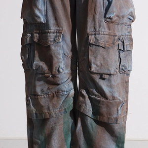 Detailed macro view of heavy distressed cargo pants with multi-pockets and vintage staining
