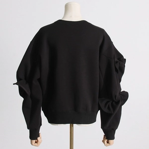 Detail of elegant black sweatshirt with oversized bow accents on the lantern sleeves