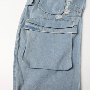 Detail of light blue denim cargo pants with large gusseted pockets and distressed edges
